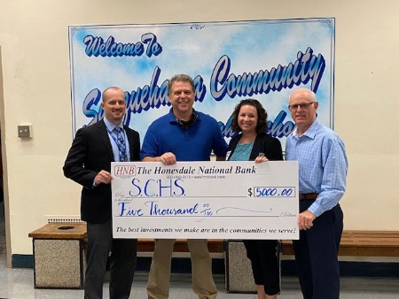 four people holding check donation for Susquehanna Community School District