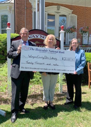 three people holding check donation for Wayne County Public Library