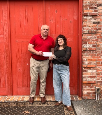 Brian Wilken hands check to Arrah Fisher, the Executive Director of the Cooperage Project.