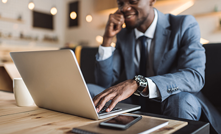 man at laptop in suit on cell 