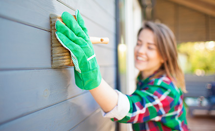 woman painting exterior of her house