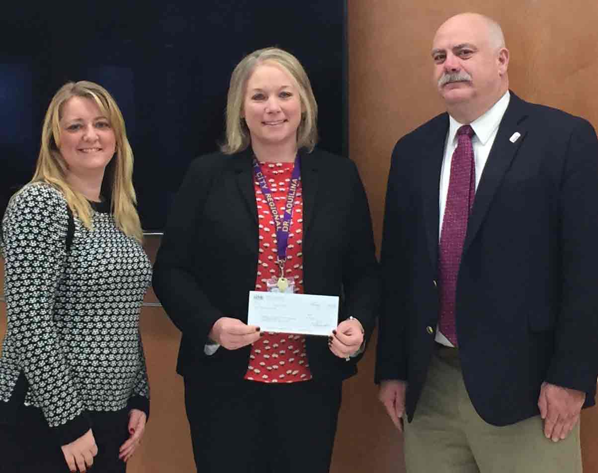 Three people standing by a check donation