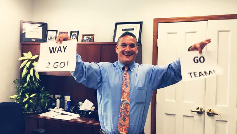 Chris Cook holding up signs of encouragement around the office