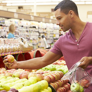 man shopping for apples at grocery store