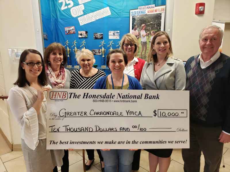 six women and one man holding large check