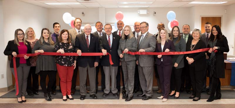 Large group of people cutting opening ribbon