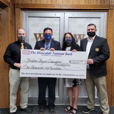 four people holding a check donation for Western Wayne Education Foundation